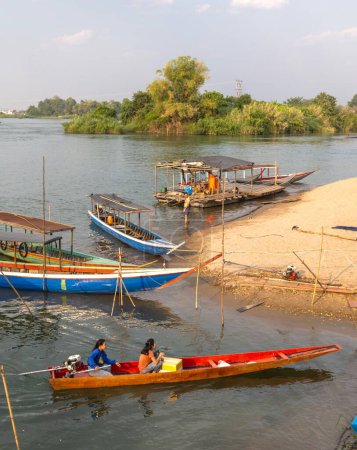 Foto de ,4000 Islands, Si Phan Don, Khong District, Laos-21 de febrero de 2023: Los viajeros van y salen en la diminuta playa del río Mekong, donde los pequeños barcos transportan a la gente hacia y desde las islas Nakasong y Don Som. - Imagen libre de derechos