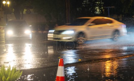 Photo for Chiang Mai,Thailand-March 16 2023: Cars rush dangerously,along the perimeter of the Old City of Chiangmai,through rain puddles in a torrential downpour. - Royalty Free Image