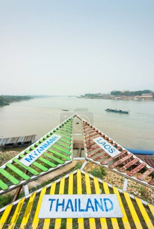 Foto de Señalización multicolor, para los turistas, que indica los lugares pertinentes de los países limítrofes de Tailandia, Myanmar y Laos, que componen el Triángulo de Oro, en la confluencia de los ríos Ruak y Mekong. - Imagen libre de derechos