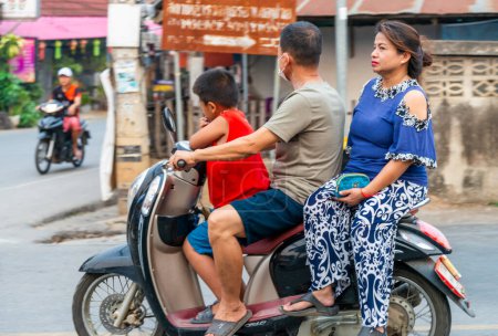 Foto de Provincia de Mae Hong Son, norte de Tailandia-10 de abril de 2023: Una vista extraña para ver, tal vez, en los países occidentales, pero en Asia la motocicleta es una forma popular de transportar múltiples personas, mascotas y bienes. - Imagen libre de derechos