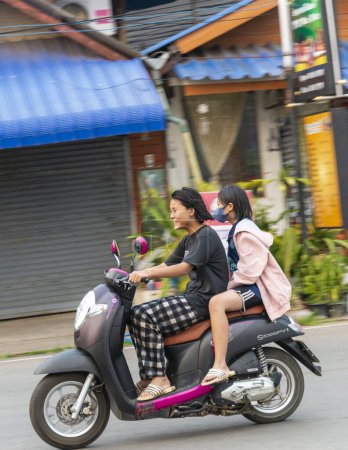 Foto de Provincia de Mae Hong Son, norte de Tailandia-10 de abril de 2023: Una vista extraña para ver, tal vez, en los países occidentales, pero en Asia la motocicleta es una forma popular de transportar múltiples personas, mascotas y bienes. - Imagen libre de derechos