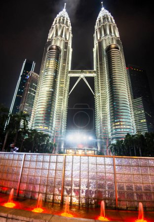 Photo for The iconic Malaysian buildings,Illuminated in a silvery light against the dark sky,with blurred movement of tiny jets of water against a reflective tiled wall. - Royalty Free Image