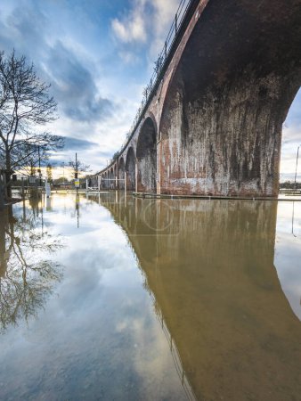 Extreme Wetterbedingungen, verursachen umfangreiche Überschwemmungen, das viktorianische Eisenbahnviadukt führt in zuvor trockenen Gebieten zu Oberleitungen, Straßen sind abgeschnitten, Felder und Autobahnen überflutet, Bäume stehen überall unter Wasser.