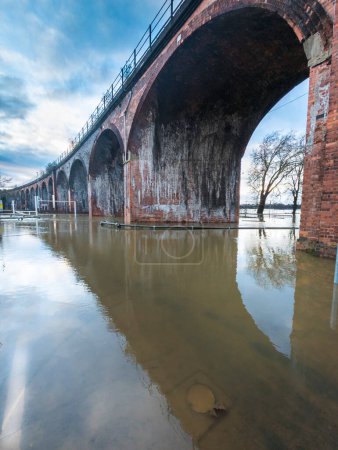 Extreme weather conditions,cause extensive flooding,the Victorian rail viaduct overhead in previously dry areas,roads cut off,flooded fields and highways,trees submerged in river water all around.