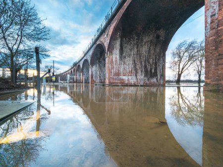 Extreme Wetterbedingungen, verursachen umfangreiche Überschwemmungen, das viktorianische Eisenbahnviadukt führt in zuvor trockenen Gebieten zu Oberleitungen, Straßen sind abgeschnitten, Felder und Autobahnen überflutet, Bäume stehen überall unter Wasser.