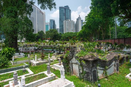 Foto de Kuala Lumpur, Malasia-16 de abril de 2023: Escondido de Jln Ampang y separado de Kampung Baru por una carretera es uno de los cementerios musulmanes más antiguos de KL. Está sombreado por banyans gigantes y árboles de lluvia. - Imagen libre de derechos