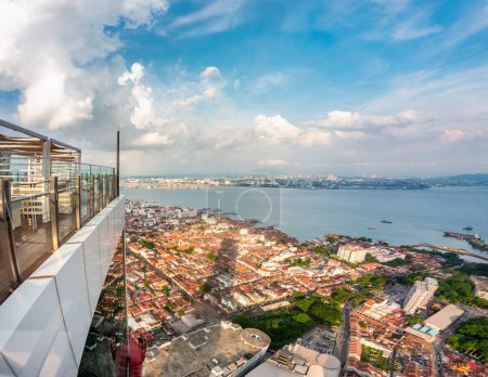 Stunning views of the city and Malacca Strait,from the rooftop of George Town's tallest building and prominent landmark,with dramatic clouds over mainland Malaysia in the background,close to sunset.