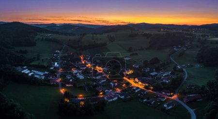 Foto de Vista aérea con un dron del pueblo de Grueb cerca de la ciudad de Grafenau en el bosque bávaro en el solsticio de verano al atardecer de la hora azul en el crepúsculo, Alemania - Imagen libre de derechos