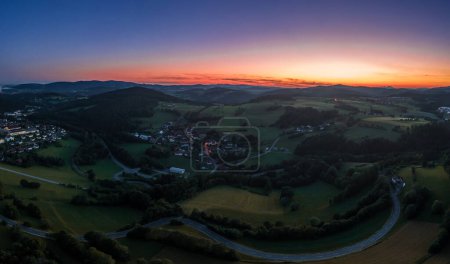 Photo for Aerial view with a drone of the village of Grueb near the town of Grafenau in the Bavarian Forest at summer solstice at blue hour sunset in twilight, Germany - Royalty Free Image