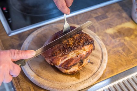 Foto de Cerdo asado casero muy abundante se corta en porciones en una tabla de madera en la cocina, Alemania - Imagen libre de derechos