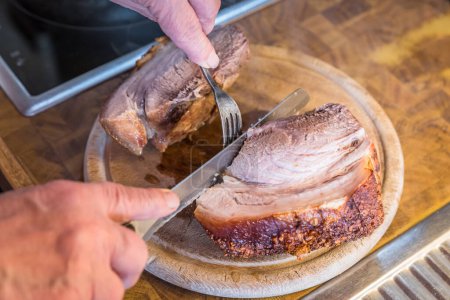 Foto de Cerdo asado casero muy abundante se corta en porciones en una tabla de madera en la cocina, Alemania - Imagen libre de derechos
