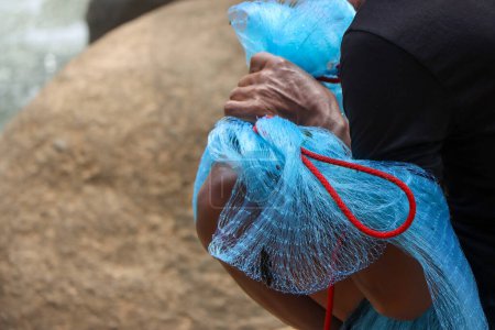 selective focus blue net in the hands of villagers catching fish along the river rapids in Thailand