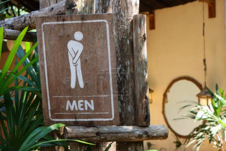 Selektiver Fokus: Männer-Toilettenschild mit schattigen Bäumen vor einer Toilette in einem Café im Wald in Thailand.