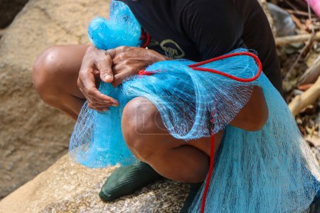 selektives blaues Netz in den Händen von Dorfbewohnern, die entlang der Stromschnellen in Thailand Fische fangen