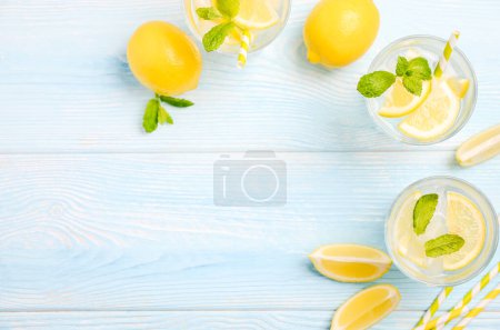 Téléchargez les photos : Boisson d'été rafraîchissante froide au citron et à la menthe sur fond de bois bleu clair, vue sur le dessus, pose plate, espace de copie
. - en image libre de droit