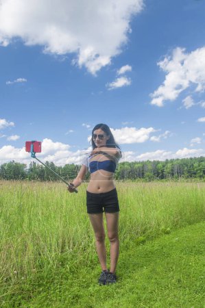 Téléchargez les photos : A beautiful chinese woman wearing sunglasses taking a selfie near tall grass in a meadow at Topsmead state forest in litchfield connecticut. - en image libre de droit