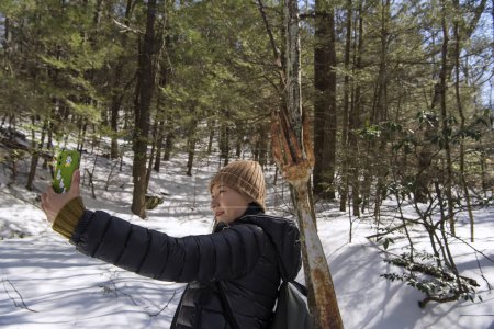 Téléchargez les photos : Une Chinoise prenant un selfie près d'une grande fourche rouillée sur le sentier de montagne jones dans le nouveau connecticut d'Hartford par une journée ensoleillée d'hiver - en image libre de droit