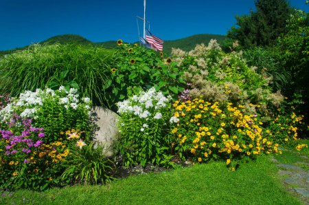 A flower garden with ornamental grass and a variety of flowers blooming in Lake George new york on a summer day.