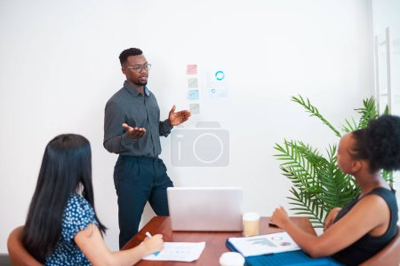 Black businessman leads meeting giving presentation in the office boardroom. High quality photo