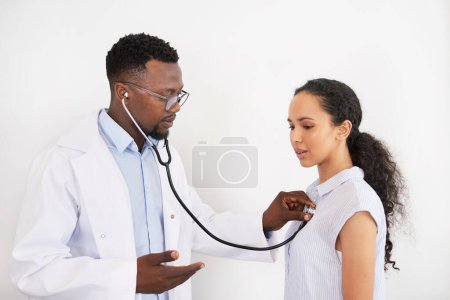 Foto de El médico negro escucha a las pacientes femeninas latidos del corazón, le dice que exhale. Foto de alta calidad - Imagen libre de derechos