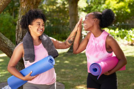 Téléchargez les photos : Deux amis noirs de haut cinq dans le parc après avoir fait du yoga, avec des tapis et des serviettes. Photo de haute qualité - en image libre de droit