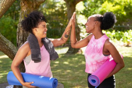 Téléchargez les photos : Deux amis noirs de haut cinq dans le parc après avoir fait du yoga, avec des tapis et des serviettes. Photo de haute qualité - en image libre de droit