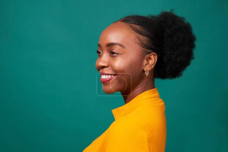 Téléchargez les photos : Belle femme noire souriant en studio, fond sarcelle, mode de vie portrait. Photo de haute qualité - en image libre de droit