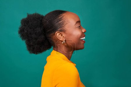 Téléchargez les photos : Belle femme noire souriant en studio, fond sarcelle, mode de vie portrait. Photo de haute qualité - en image libre de droit