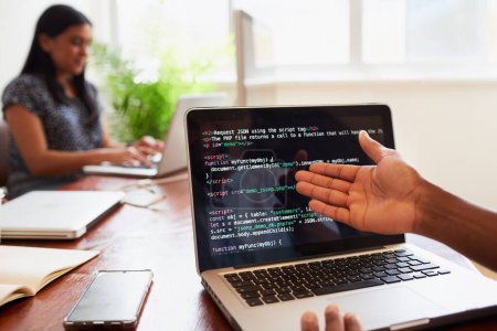 Por encima de la toma de hombro del gesto joven desarrollador masculino para codificar en el ordenador portátil en la oficina. Foto de alta calidad