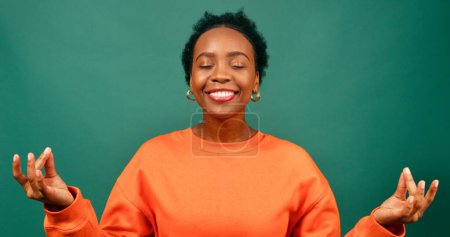 Téléchargez les photos : Belle femme noire respire et médite, se sentant relax heureux, studio vert. Photo de haute qualité - en image libre de droit