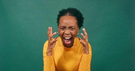 Téléchargez les photos : Femme en colère crie et crie avec des gestes de main, studio vert. Photo de haute qualité - en image libre de droit