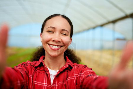 Granjera multi-étnica tomando una selfie, invernadero en el fondo. Foto de alta calidad
