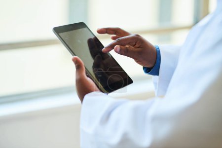 Close-up shot of a doctors hands using a digital tablet in a modern hospital. The image highlights the integration of technology in healthcare to enhance patient care and medical management.