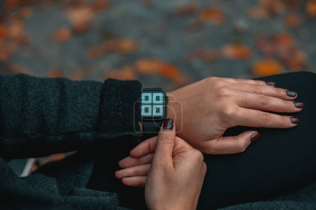 Photo for Woman looking at smartwatch on her hand. Time on the clock 12-00.Close up view with blurred background. Full frame. - Royalty Free Image