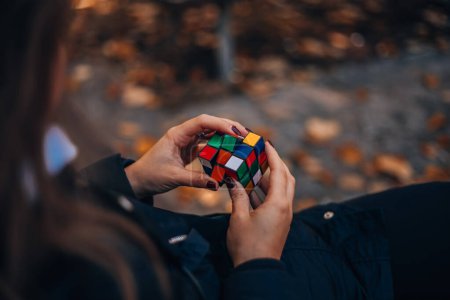 Photo for Italia, Milano 15.11.2023: Girl holding a Rubik cube in her hand. Business woman looking for a solution to a puzzle. Rebus, puzzle. Concept of creative ideas in . High quality photo. - Royalty Free Image