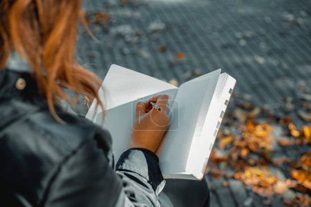 Photo for Woman with notepad. Close-up of a young girl writing into her diary, in the park. A woman writes in a notebook with a pen on the street. Web banner. Full Frame. High quality photo - Royalty Free Image