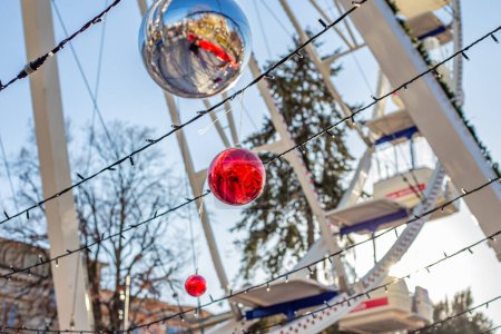 Photo for Christmas balls decorate the entrance to the Ferris wheel. Ferris wheel at the Christmas market in the city center of Bergamo, Italy. - Royalty Free Image