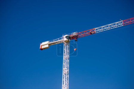 Two construction tower cranes at a construction site against a blue sky with clouds. Modern high-rise office building under construction. Copyspace. Italy, Milan. 