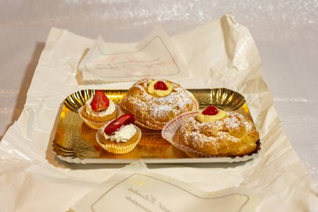 Italian dessert Zeppole di San Giuseppe, zeppola baked puffs made from choux pastry, filled and decorated with custard cream and cherry.