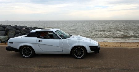 Photo for FELIXSTOWE, SUFFOLK, ENGLAND - MAY 01, 2022:  Classic  Triumph TR7  car parked on seafront promenade beach and sea in background. - Royalty Free Image