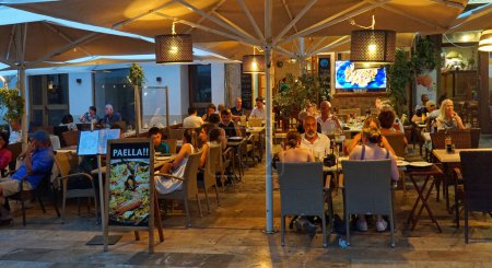 Foto de VENDEDOR, MALLORCA, ESPAÑA - 21 DE JUNIO DE 2022: Los comensales que comen en el restaurante por la noche afuera. - Imagen libre de derechos