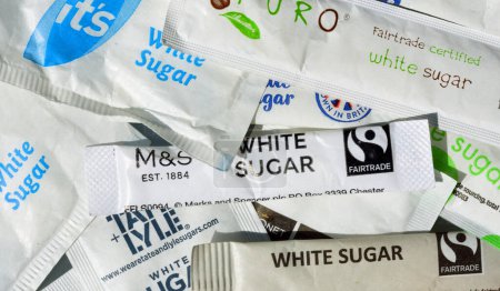 Photo for ST NEOTS, CAMBRIDGESHIRE, ENGLAND -  JULY 20, 2023: Small packets of white sugar with various logos - Royalty Free Image