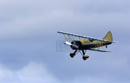Foto de PEQUEÑO GRANSDEN, CAMBRIDGESHIRE, INGLATERRA - 27 DE AGOSTO DE 2022: Vintage Waco UPF-7 biplano en vuelo contra nubes. - Imagen libre de derechos