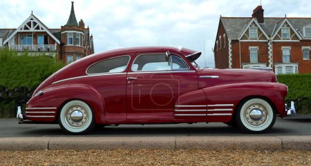 Photo for FELIXSTOWE, SUFFOLK, ENGLAND - AUGUST 23, 2014: Classic Red Chevrolet Fleetline Car isolated by hedge - Royalty Free Image