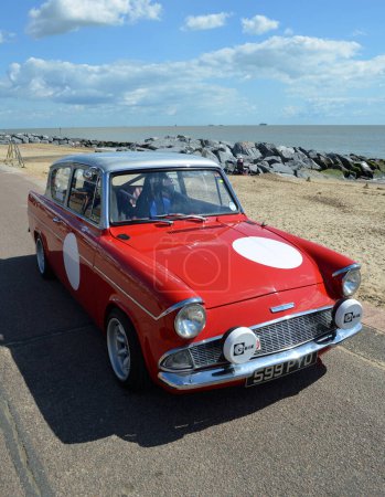 Photo for FELIXSTOWE, SUFFOLK, ENGLAND - AUGUST 23, 2014: Classic Red Ford Anglia in vintage car rally on Felixstowe seafront. - Royalty Free Image