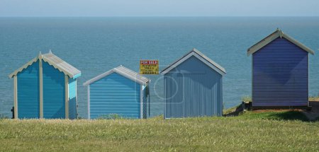 Photo for FELIXSTOWE, SUFFOLK, ENGLAND -  JUNE 14, 2023: Beach huts in a row sea in background 1 hut with for sale board. - Royalty Free Image