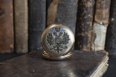 Photo for Gold pocket watch "Pavel Bure" on a gold pendant. Royal Russia. pocket watch on a dark background with books. Image of an antique gold pocket watch on an old antique book. - Royalty Free Image