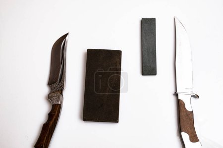 Téléchargez les photos : Aiguisage couteau, couteau sur fond blanc isolé avec pierre abrasive. le concept du travail d'un maître aiguiseur de couteau - en image libre de droit