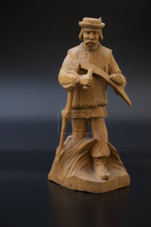 Téléchargez les photos : Figurine en bois faite à la main sur fond noir. grand-père avec une faux dans le champ de foin - en image libre de droit