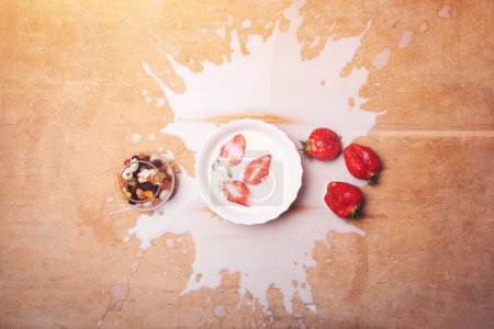 Téléchargez les photos : Assiette avec petit déjeuner avec lait renversé, fraises, noix sur fond en bois. Photo de haute qualité - en image libre de droit